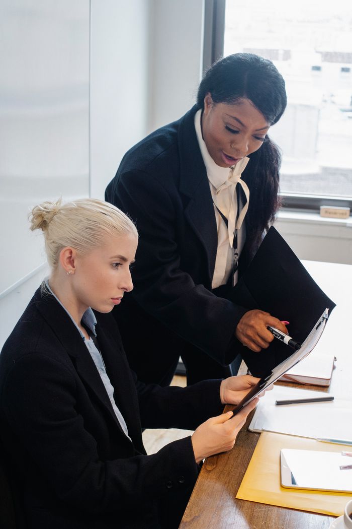 Diverse women in formal clothes gathering in modern workspace and discussing business ideas while working together